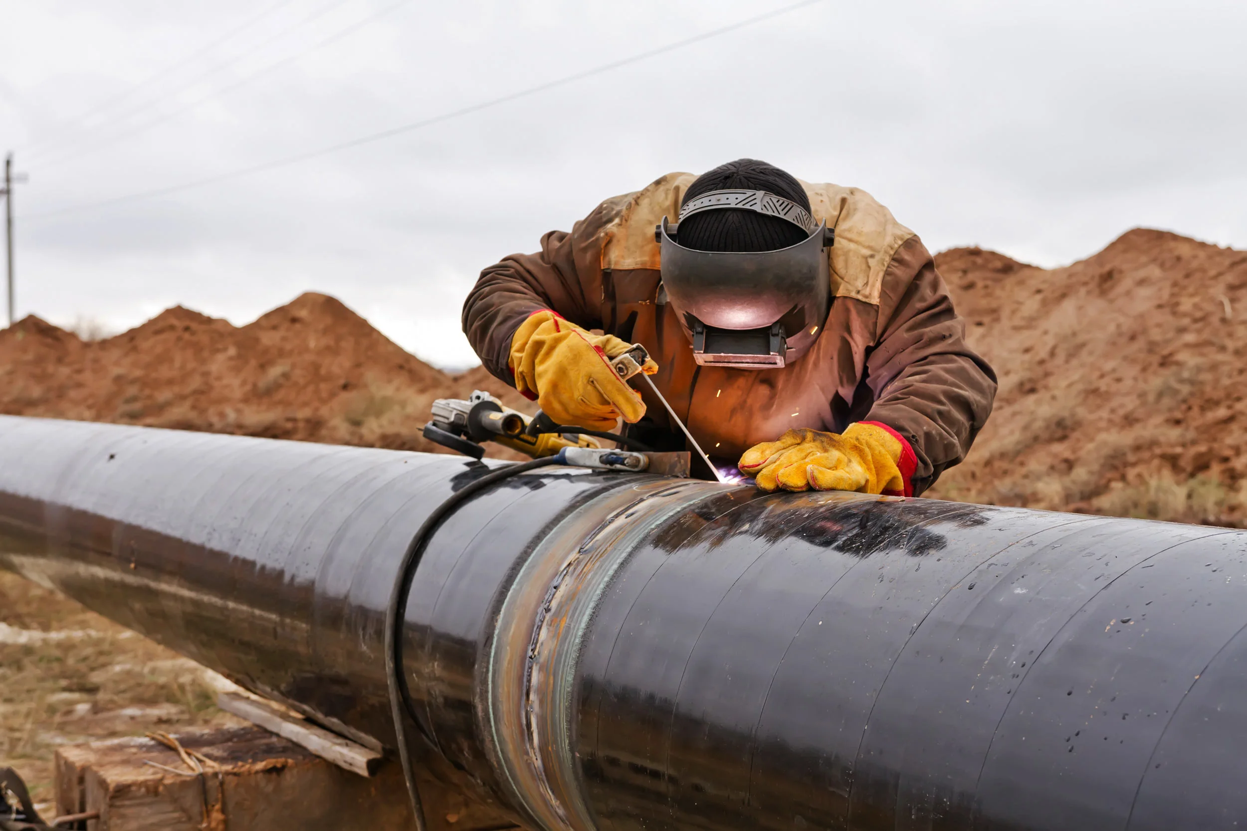 Welder joining a pipeline section in the field